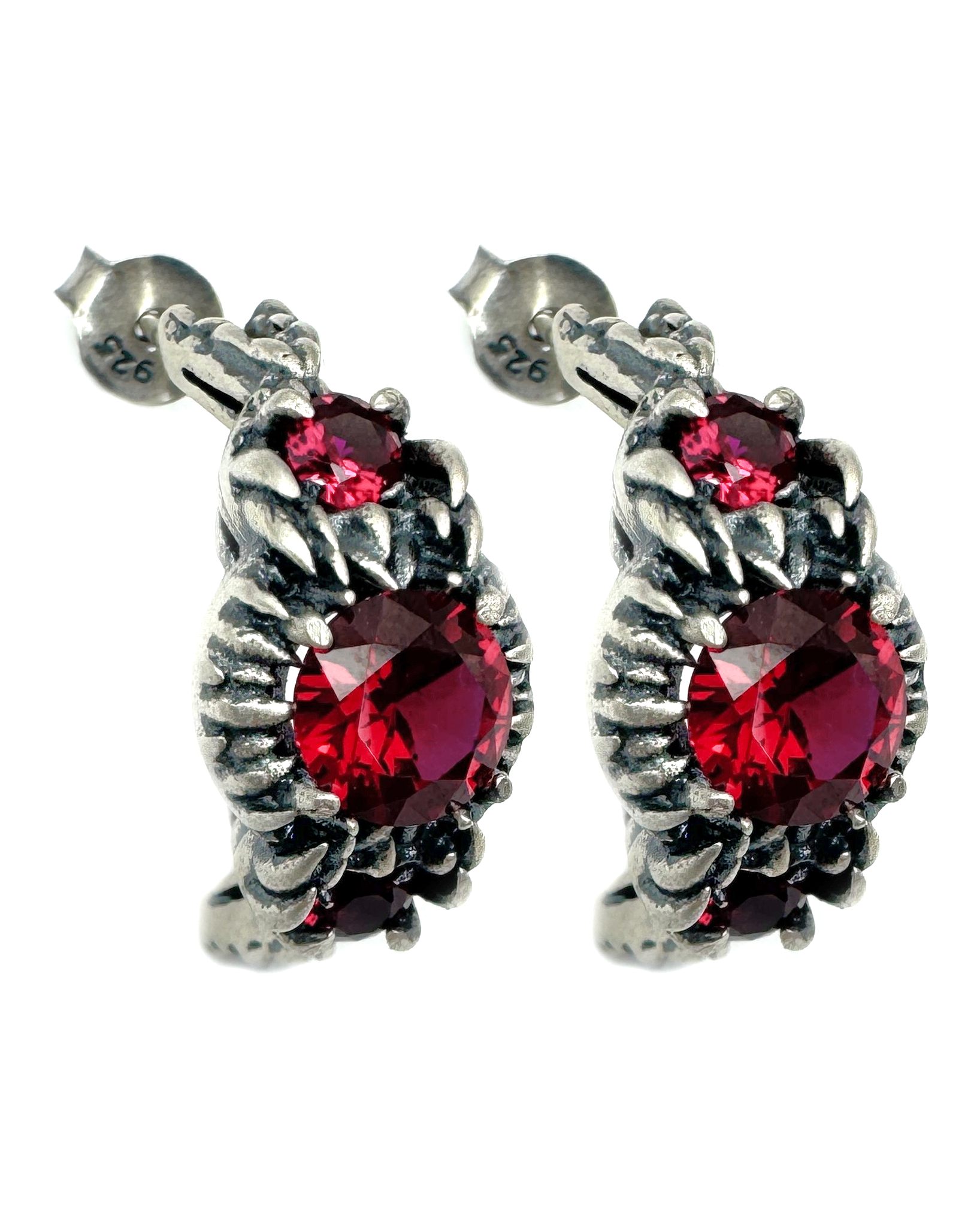 A pair of silver earrings with claw like prongs holding a ruby.