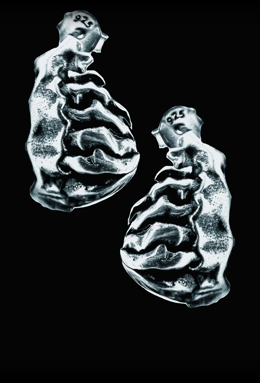 Two metallic earrings representing teeth on a black background