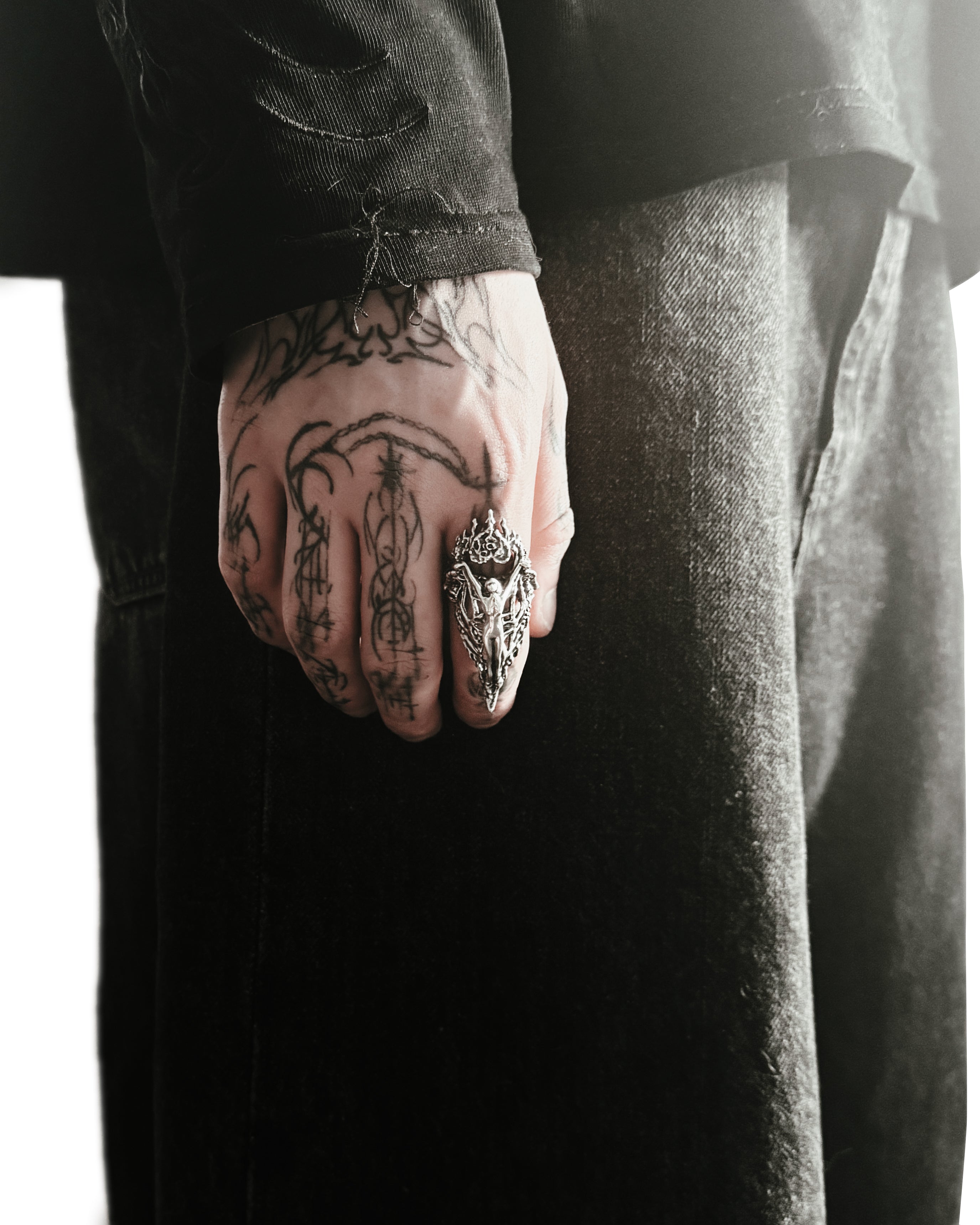 A sterling silver ring with a intricate design resembling armor and an angelic figure, featuring a textured and raised pattern on a male hand.