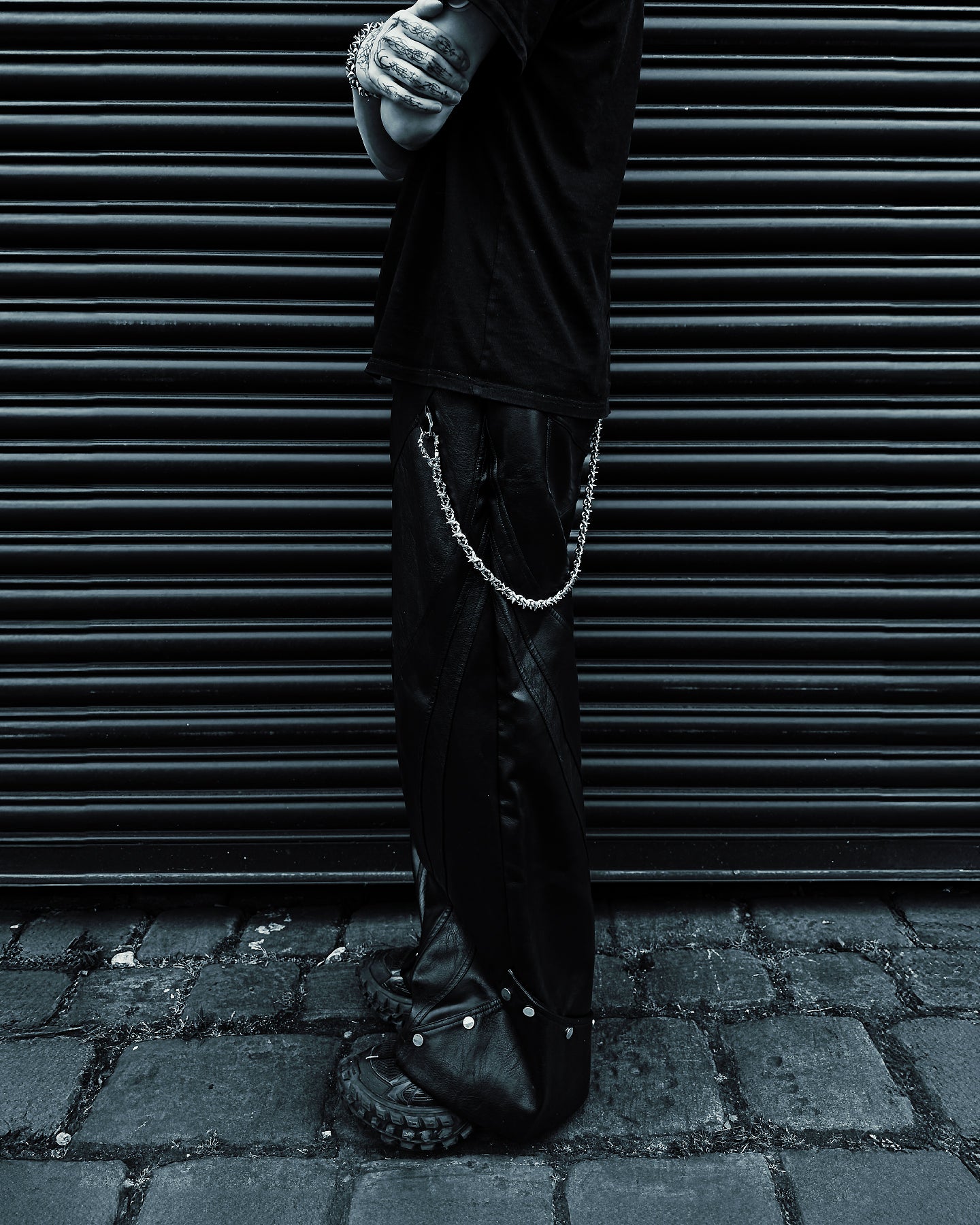 Person wearing black pants with a wallet chain detail against a dark background