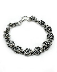 A bracelet made of silver with a series of skull and rose designs.